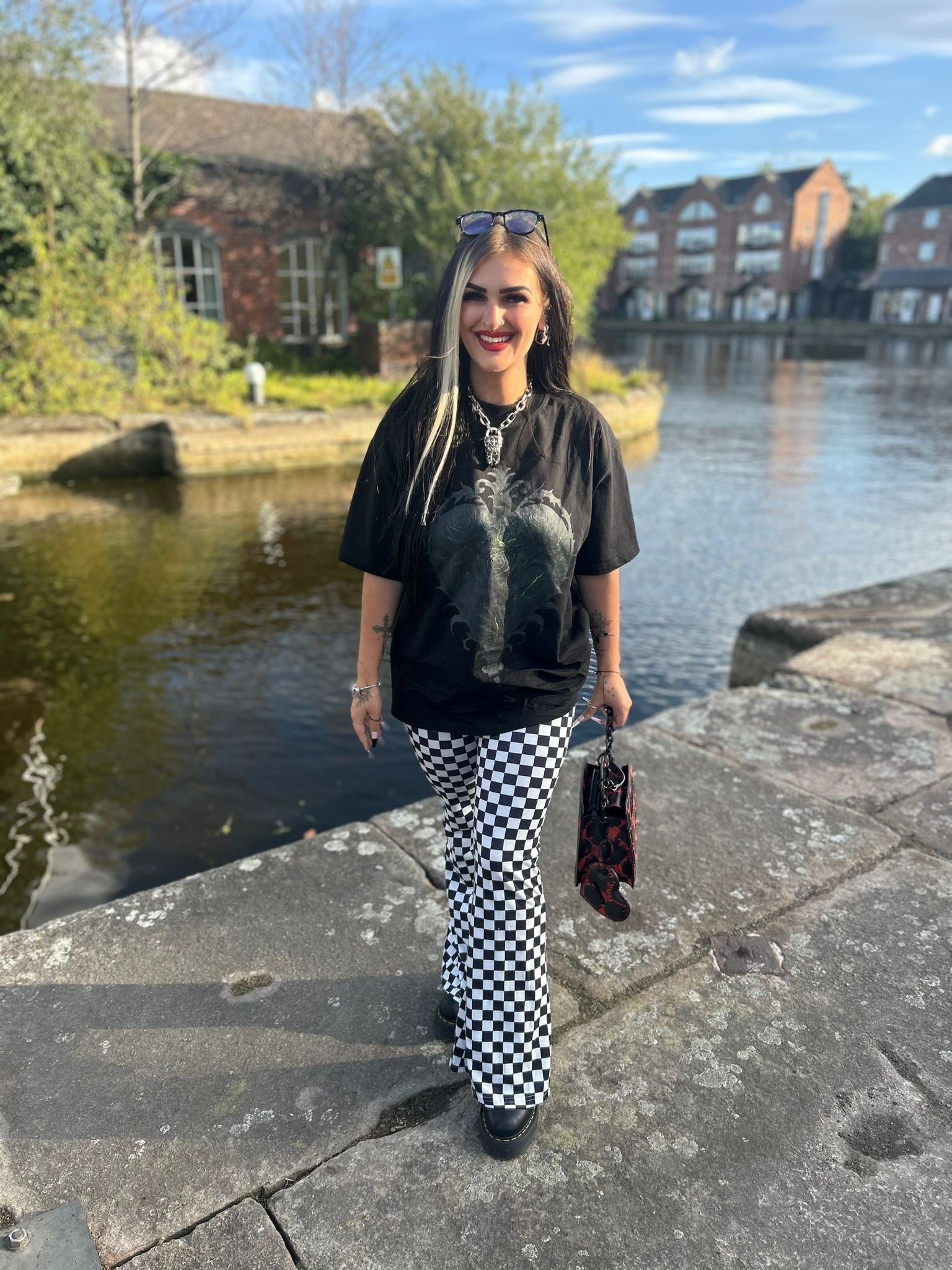 Model wearing ANG3L “Poison & Beauty” Oversized Gothic Tee, front design visible, styled with checkered trousers and black boots.