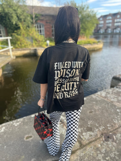 Close-up of gothic print text on back of ANG3L “Poison & Beauty” Oversized Gothic Tee, reading “Filled with poison, blessed with beauty and rage”.
